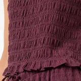 Top sin mangas de color bordó, confeccionado en tejido con textura fruncida. Presenta cuello redondo con detalle de volado y ruedo con terminación similar.