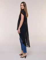Blusa larga negra de gasa liviana con silueta amplia y desestructurada, escote redondo, mangas cortas caídas y bajo asimétrico más largo en la parte posterior.