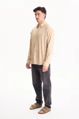 Camisa de lino de manga larga, color beige, con cuello clásico y cierre frontal de botones.