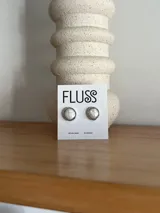 Aros tipo botón con perlas de río engarzadas en metal plateado.