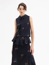 Top sin mangas color azul marino con cuello camisero y peplum en la cintura. Presenta un estampado de cerezas.