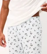 Pijama largo para hombre confeccionado en algodón, compuesto por una remera de manga corta blanca con cuello redondo celeste y estampa frontal de Snoopy, y un pantalón largo celeste con estampado general de Snoopy y cintura elástica.