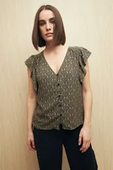 Blusa estampada con motivos de hojas en tonos beige y negro, con escote en V, botones al frente y volados en los hombros.