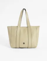 Cartera tipo shopper de cuero vegano en color beige, con diseño de doble asa fija y pespuntes verticales decorativos. Incluye un logo metálico pequeño en la parte inferior central y cuenta con una correa larga desmontable y regulable.