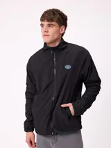 Campera reversible con cuello alto y cierre frontal. Un lado presenta tejido de polar con estampado geométrico en tonos verdes y bolsillo con cierre en el pecho, mientras que el otro lado es de nylon. Cuenta con puños elásticos y bolsillos laterales.