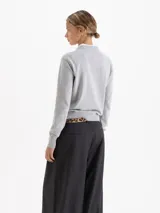 Sweater de tejido de punto color naranja, con cuello redondo, mangas largas y puños acanalados. Presenta una textura suave y un diseño clásico de calce estructurado.