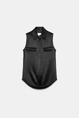 Camisa sin mangas de tejido satinado, con cuello solapa, cierre frontal con botones ocultos y bolsillos de plastrón con solapa en el delantero. Presenta un bajo asimétrico y corte recto.