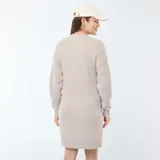 Vestido corto color beige, tipo sweater, de tejido de punto con cuello redondo y manga larga. Presenta una abertura frontal con botones para facilitar la lactancia.