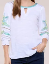 Blusa blanca de silueta semi entallada, confeccionada en tejido texturado. Cuenta con escote en V con abertura y vivo bordado multicolor, mangas 3/4 abullonadas con bordados, calados y puños elásticos.