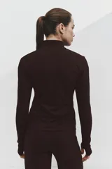 Campera deportiva corta color bordó con tecnología SoftMove y DryMove, de corte ajustado, cuello alto, cierre frontal y mangas largas con abertura para el pulgar.