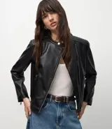 Campera biker negra de poliuretano, con cierre frontal asimétrico de cremallera, bolsillos laterales con cierre y detalle capitoneado en los hombros.