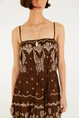 Vestido largo marrón con estampado estilo paisley y mariposas en tonos crudos, de corte fluido, con tirantes finos y diseño escalonado en la falda.
