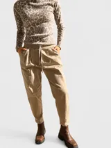 Pantalón tipo babucha de tela liviana con efecto gabardina, color beige. Presenta cintura elastizada con cordón ajustable, pinzas delanteras y bolsillos laterales funcionales.