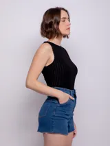 Short de jean negro con cuatro bolsillos, presillas, terminación desflecada, botón y cierre metálico.