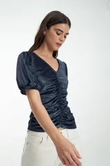Blusa azul de terciopelo con escote en V, frunce al frente y mangas abullonadas con puños.