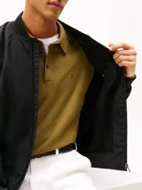 Campera bomber Tommy Hilfiger de color negro, confeccionada con tejido técnico de nailon reciclado y poliamida resistente al viento y la humedad ligera. Presenta diseño de corte clásico con cierre frontal de cremallera, cuello, puños y dobladillo en rib elástico, y dos bolsillos laterales de ojal. Incluye el logo monotipo bordado discretamente en el pecho.