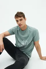 Remera verde de manga corta con cuello redondo y estampado blanco con la inscripción 'Budapest Hungary' y un dibujo de un edificio.