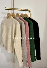 Sweater de tejido de punto con diseño de trenzas verticales, cuello redondo y mangas largas con puños ajustados que presentan detalle de botones metálicos.