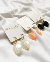 Par de aros colgantes con aro dorado y dije de piedra negra veteada.