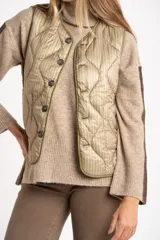 Chaleco acolchado color verde oliva, con diseño capitoneado de ondas, cierre frontal con botones y bolsillos laterales.