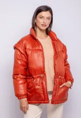 Campera puffer de diseño ochentoso con mangas removibles que permiten convertirla en chaleco. Presenta cuello alto, cierre frontal y cordón ajustable en la cintura.