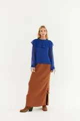 Blusa verde oliva con volados en el cuello y mangas largas transparentes con puños elásticos.