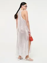 Vestido largo de corte recto con escote redondo y tirantes anchos, completamente cubierto de lentejuelas brillantes. Presenta tajos laterales en el ruedo.