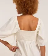 Vestido corto evasé color celeste, con escote en V, mangas cortas amplias, recorte cutout en los laterales de la cintura y volado en el bajo.