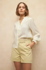 Short sastrero color amarillo pálido de algodón, con pretina ancha, doble botón forrado a tono, dobladillos y bolsillos en los laterales.