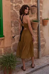 Vestido largo color ocre, confeccionado en tela acanalada. De calce estilo halter, cuenta con una falda amplia con cortes de formas curvas.