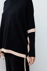 Polera de tejido de punto con cuello alto, diseño holgado y detalles en color contraste en los laterales y ruedo.