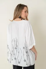 Blusa color ladrillo con estampado de flores y líneas negras, de corte holgado, cuello redondo y mangas cortas con puños elásticos.