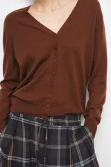 Chaqueta tipo cárdigan de lana, color beige, con escote en pico, manga larga y cierre frontal con botones.