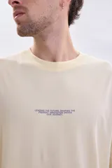 Remera oversize de manga corta en color amarillo, con cuello redondo y una pequeña estampa frontal con texto en el pecho.