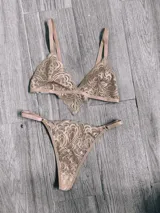 Conjunto de ropa interior color canela de encaje floral, compuesto por corpiño triangular sin aro y tanga.
