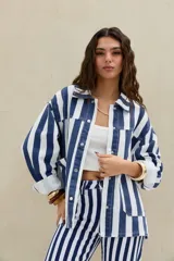 Campera de denim con diseño de rayas verticales en azul y blanco, de corte oversize, con cuello clásico, cierre frontal con botones metálicos y bolsillos appliqués en el frente.
