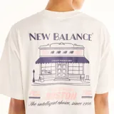 Remera New Balance de manga corta y corte oversize, color blanco, con pequeño estampado gráfico en el pecho.