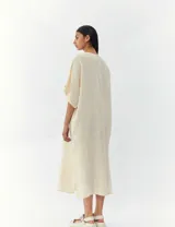 Vestido largo color crema, de corte amplio y mangas cortas.