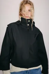 Cazadora negra ZW Collection de cuello subido con capucha, manga larga y bolsillos delanteros. Presenta forro interior a contraste y cierre frontal cruzado con botones a presión dorados.