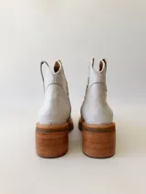 Botas texanas de cuero color gris claro, con caña baja, puntera cuadrada y taco de madera.