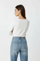 Remera de manga larga color beige, con cuello redondo y estampado frontal con efecto foil metalizado y texto.