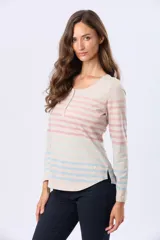 Remera de manga larga con cuello redondo y cierre frontal parcial con botones. Presenta un diseño de rayas horizontales en tonos pastel sobre una base beige, con aberturas laterales en el ruedo.