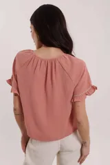 Blusa rosa con cuello redondo, mangas cortas con volados y detalle de encaje vertical en el frente.