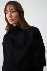 Capita de punto acanalado color negro, con cuello alto y diseño sin mangas.