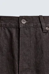 Jeans flare fit de denim negro, con tiro medio, corte ajustado en la parte superior y ligeramente acampanado desde la rodilla. Diseño de cinco bolsillos y cierre frontal con botones.