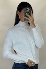 Buzo de hilo de punto con diseño de trenzas verticales, cuello alto y cadena metálica decorativa incorporada en la parte frontal.
