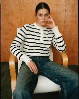 Sweater de punto a rayas horizontales marrones y blancas, con cuello redondo, cierre frontal parcial con botones y detalles de puntilla blanca en el cuello y los puños.