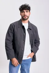 Campera de color negro para hombre, con cuello camisero, cierre frontal de botones y bolsillos aplicados en el frente.