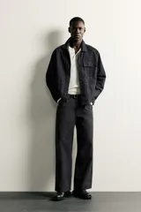 Jeans relaxed fit de corte recto y tiro medio, color negro, confeccionados en denim de algodón rígido con diseño de cinco bolsillos y cierre frontal de cremallera y botón.