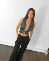 Chaleco gris de ecocuero con escote en V y cinturón con hebilla metálica.